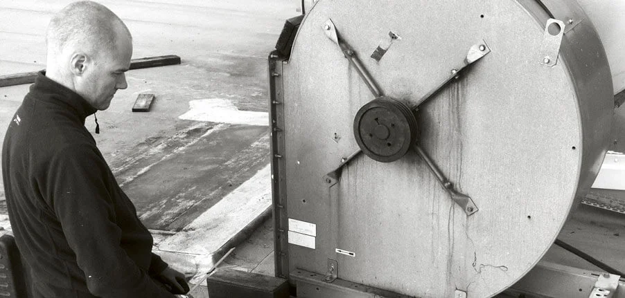 Medarbetare som inspekterar ett ventilationsaggregat på ett tak.